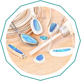 Various opal jewelry pieces, including rings and necklaces, displayed on a wooden surface.  From a guide on jewelry making tools.