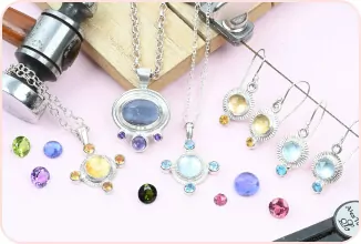 Colorful gemstone jewelry set including necklaces, earrings, and loose gems displayed on a light pink surface.