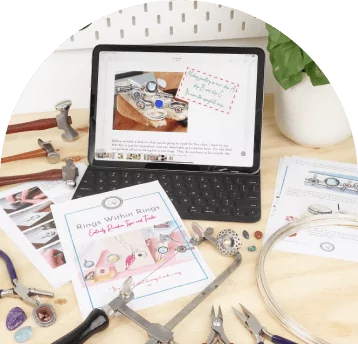 Tablet displaying jewelry design, surrounded by tools, instructions, and materials on a worktable.
