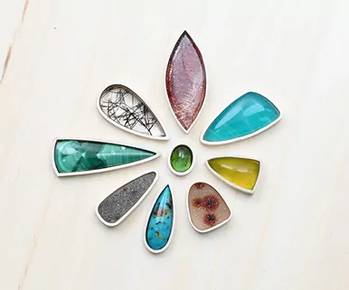 Various gemstones arranged in a flower shape on a light wooden surface.