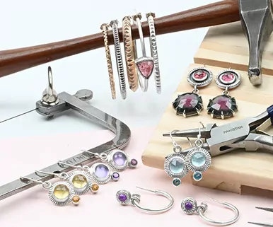 A variety of silver hoop earrings and colorful gemstone earrings displayed with jewelry-making tools.