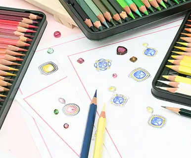 Colored pencils and jewel sketches on paper, surrounded by colored pencil sets and erasers.