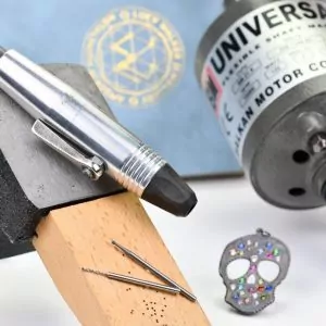 flex shaft drill for jewelry making with flush set pendant in back ground and drill bits for jewelry making in foreground
