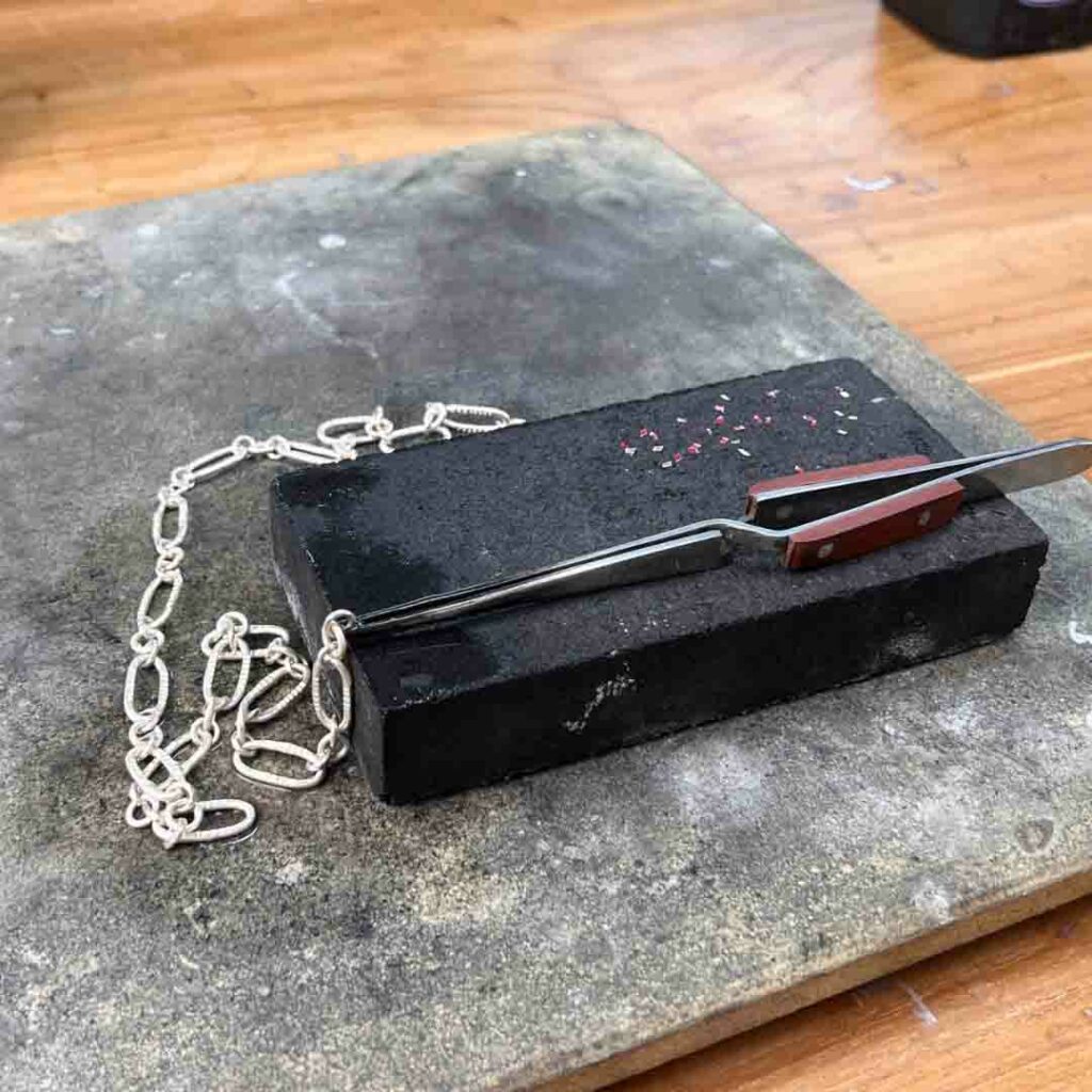 Holding a sterling silver chain in cross locking tweezers for soldering