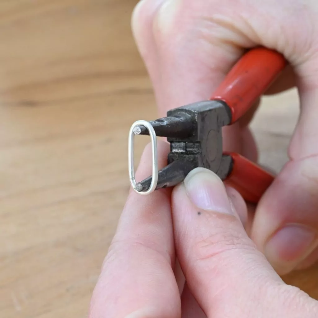 Using ring opening pliers to create a paperclip chain link