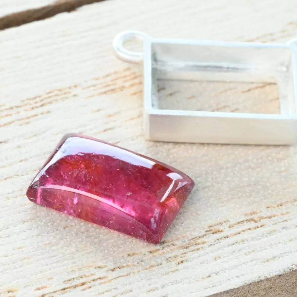 Tourmaline cabochon next to a silver bezel