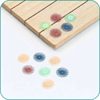 Colorful round brush sander discs scattered on a wooden surface and white background.