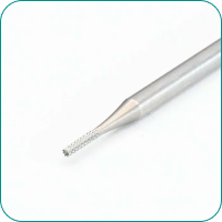 Close-up of a metallic dental bur with a textured tip, used for dental procedures, on a white background.