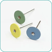 Three sanding discs with metal stems in green, yellow, and blue on a white background.
