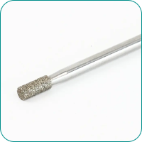 Close-up of a silver cylindrical metal tool with a textured, rough tip, likely used for grinding or drilling.