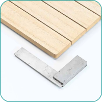 A wooden board with grooves and an L-shaped metal square on a white background.