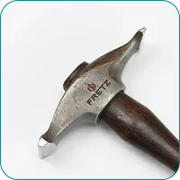 A metal hammer with a wooden handle, engraved with "Fretz" on the head, lies on a white surface.