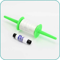 Green spool holder with clear thread, next to a small black and white cylindrical item.