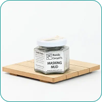 A jar of "Masking Mud" on a wooden platform, featuring a white label and white lid.