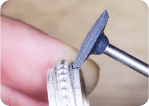 Close-up of a hand using a rotary tool to polish the edge of a ring. From a class on how to make a ring with beaded wire.