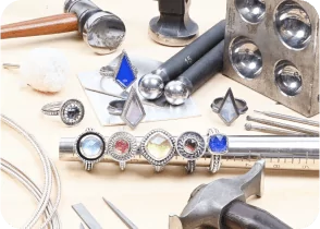 Jewelry-making tools and rings with colorful gemstones on a table. From a class on how to make a ring with beaded wire.