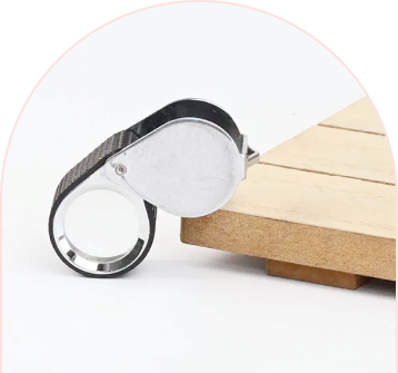 Magnifying glass with a black grip and silver rim resting on a wooden surface.