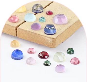 Assorted gemstones of various colors and cuts displayed on wooden blocks and a white surface.