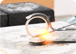 Close-up of a jewelry crafting process, with a glowing molten area being worked on by a tool. From a class on how to make a ring with beaded wire.