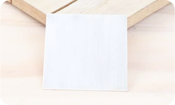A blank white square card on a light wooden surface.