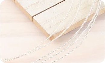 Silver chains draped over a light wooden surface with a light background.