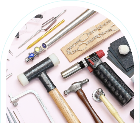 Jewelry-making tools and materials arranged on a pink surface.