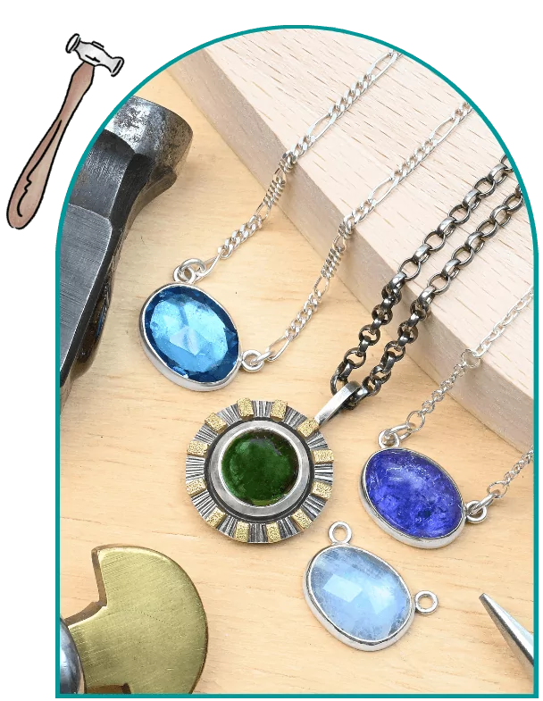 Jewelry pendants with blue and green stones on a wooden surface, surrounded by tools.  From a class on bezel setting for beginners.
