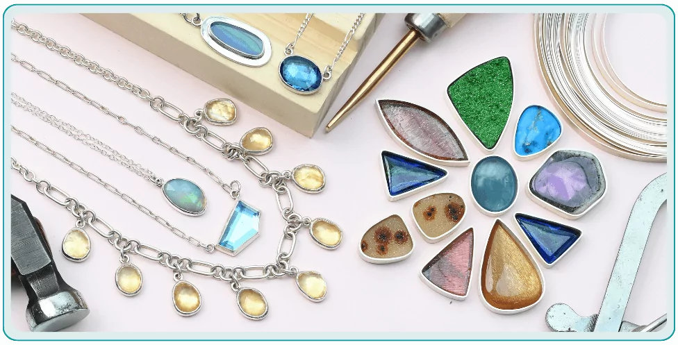 Various gemstone jewelry and tools arranged neatly, featuring necklaces and colorful pendants on a light background.  From a class on bezel setting for beginners.