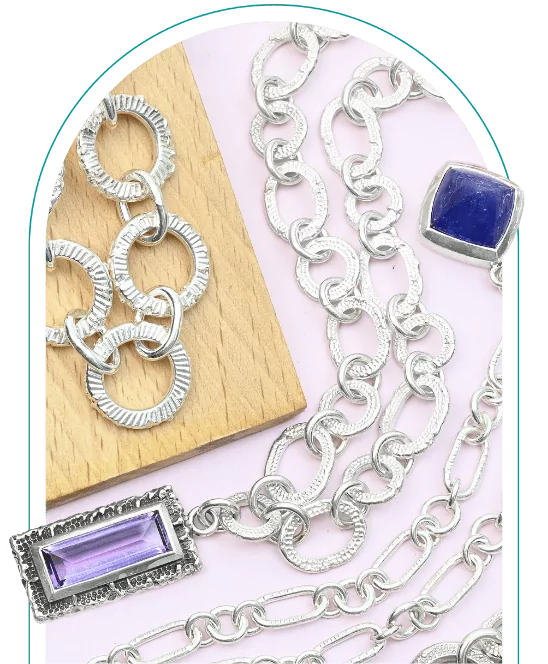 Silver chains with geometric pattern pendants on a pink background, including rectangular and square blue stones.  From a class on chain making and soldering silver.