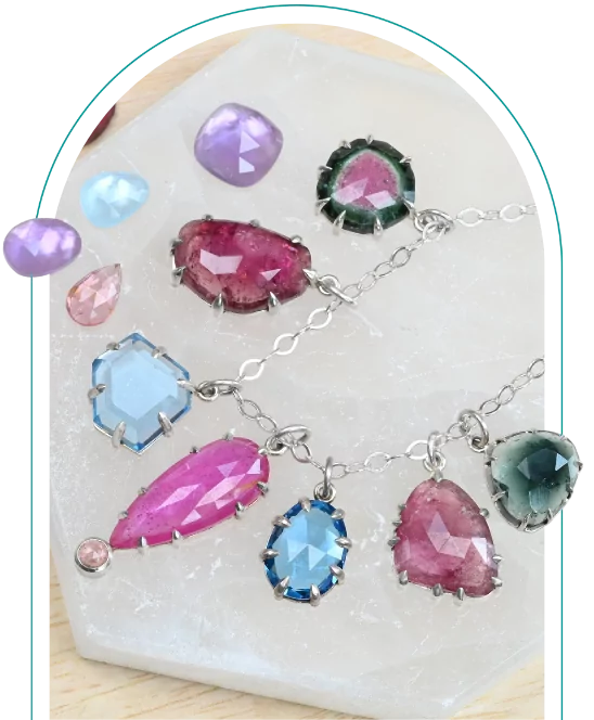 Gemstone jewelry and loose stones displayed on a marble surface.  From a class on prong setting gemstones.
