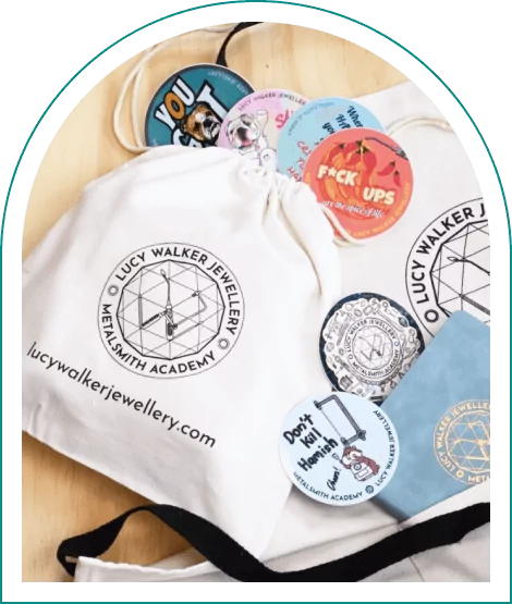 Jewelry academy bag with colorful stickers and patches on a wooden surface.
